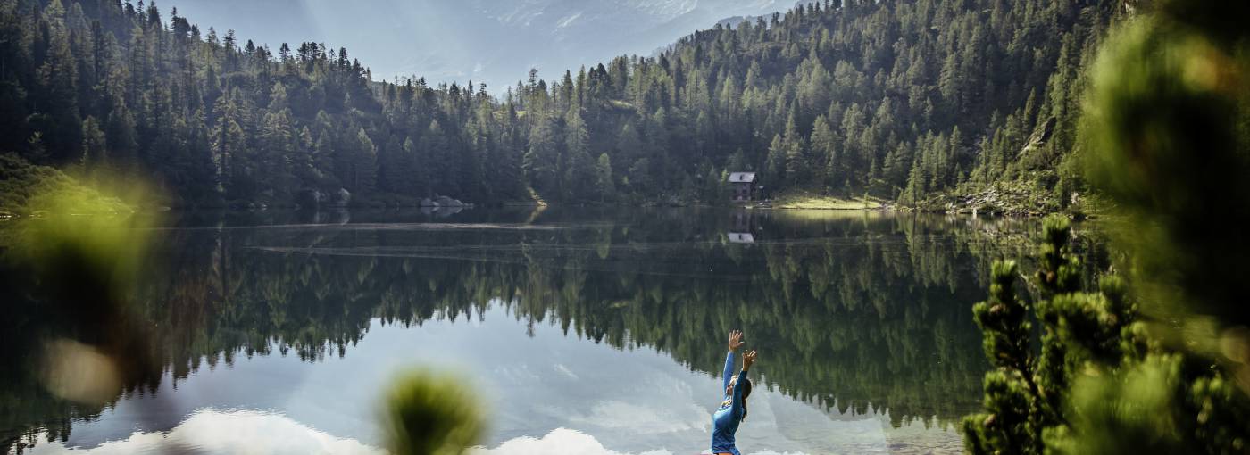Frau in Yogaposition vor Bergsee